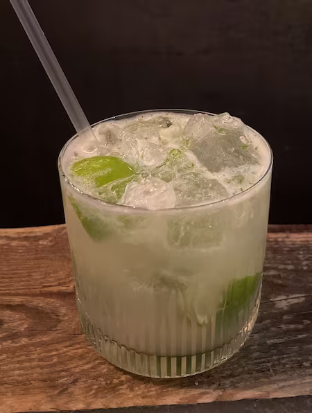 Capirinha cocktail in tumbler glassware with crushed ice and straw