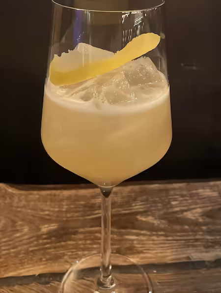 Light yellow color in a white wine glass lemon zest as garnish on wooden table