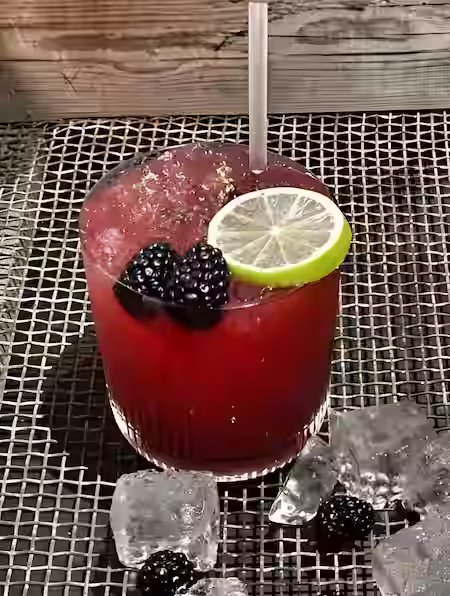Tumbler Filled With Red Liquid Blackberry And Lime As Garnish
